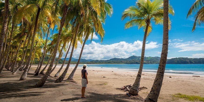 Kvinde står på stranden i Playa Sámara og kigger på vandet