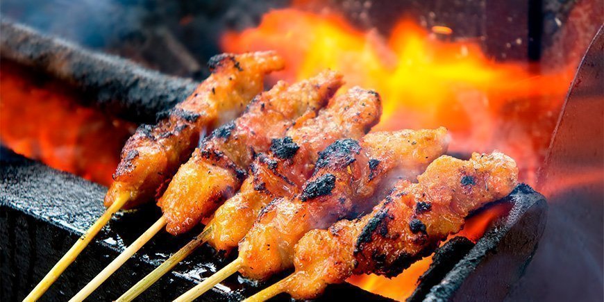 Satay-kylling, der bliver grillet over ilden