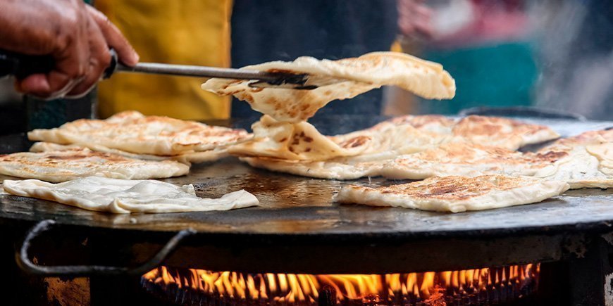 Roti Canai-brød bliver stegt på en stor pande