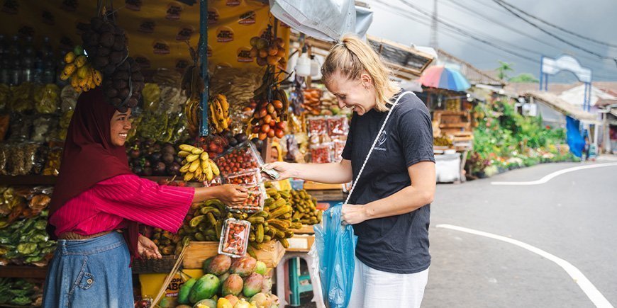 Kvinde i TourCompass t-shirt betaler kvinde for varer i en gadebod