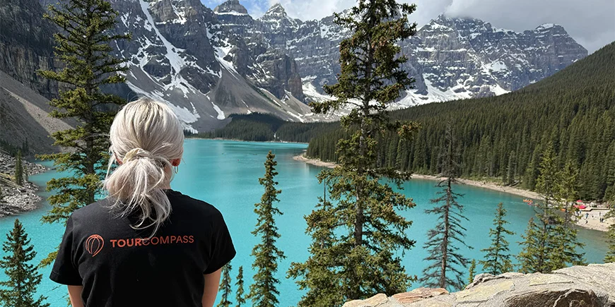Kvinde i TourCompass-t-shirt kigger ud over vandet ved Lake Louise i Canada